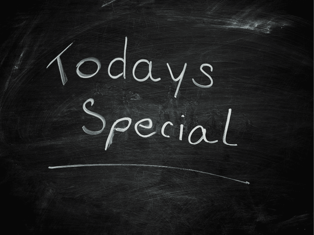 A handwritten message on a dark, weathered chalkboard that reads "Todays Special" in white chalk. The handwriting is casual and slightly slanted, with a thin white line underlined beneath the word "Special." The chalkboard surface shows faint smudges and erased chalk marks, giving it a rustic or cafe-style appearance.