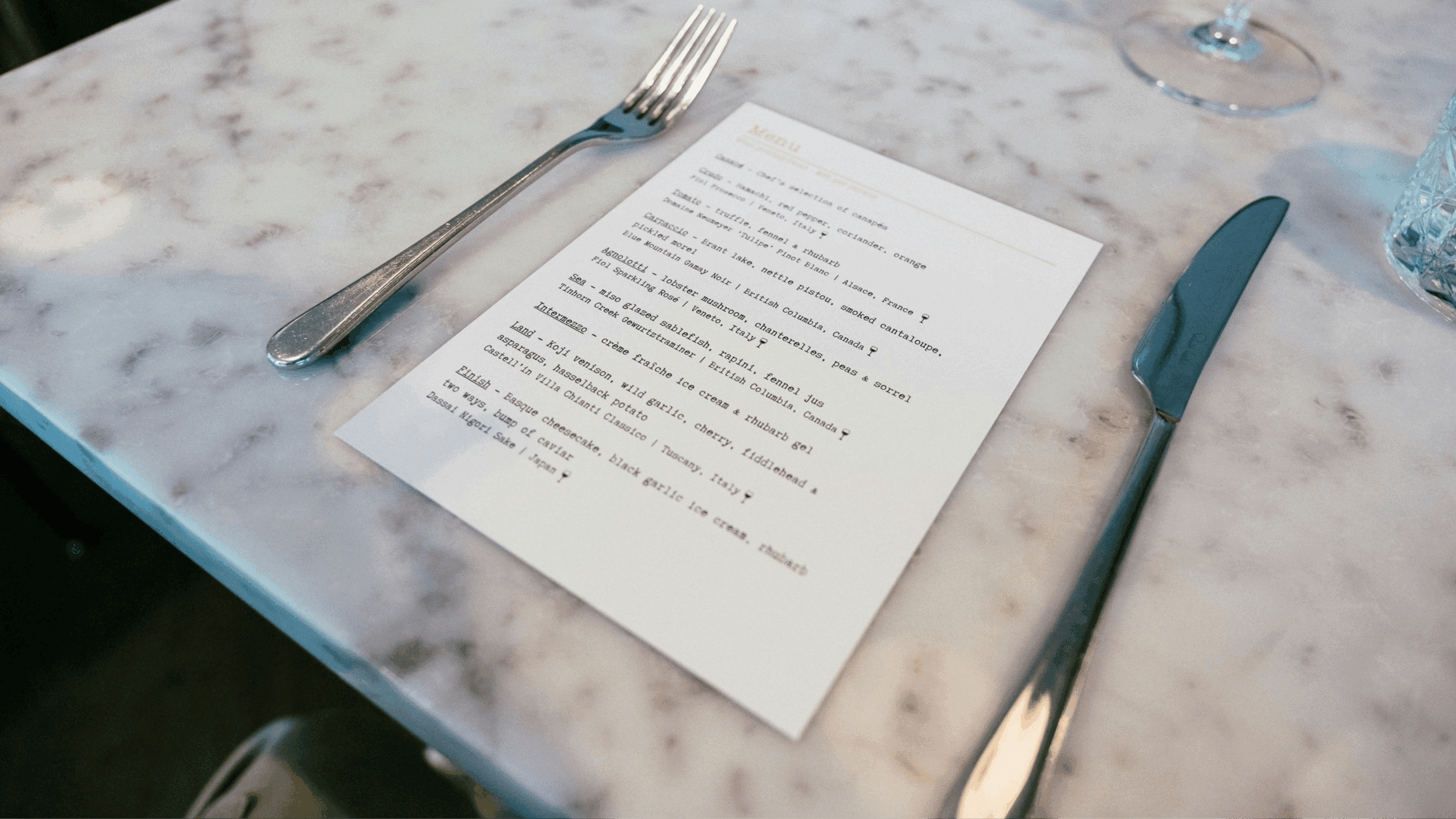 Photo of a printed menu on a restaurant grey table with a fork on the left and a knife on the right
